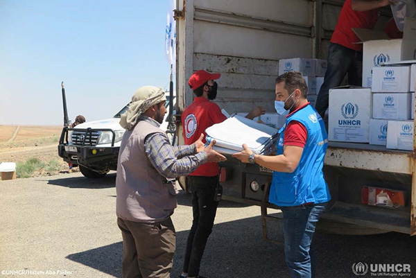 支援物資を帰還民に渡すUNHCRスタッフ