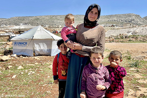 UNHCRのテントの側に立つ被災者の一家
